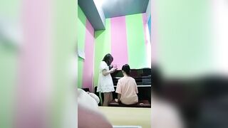 어른 장난감을 끼고 학생들에게 수업을 하는 피아노 선생님